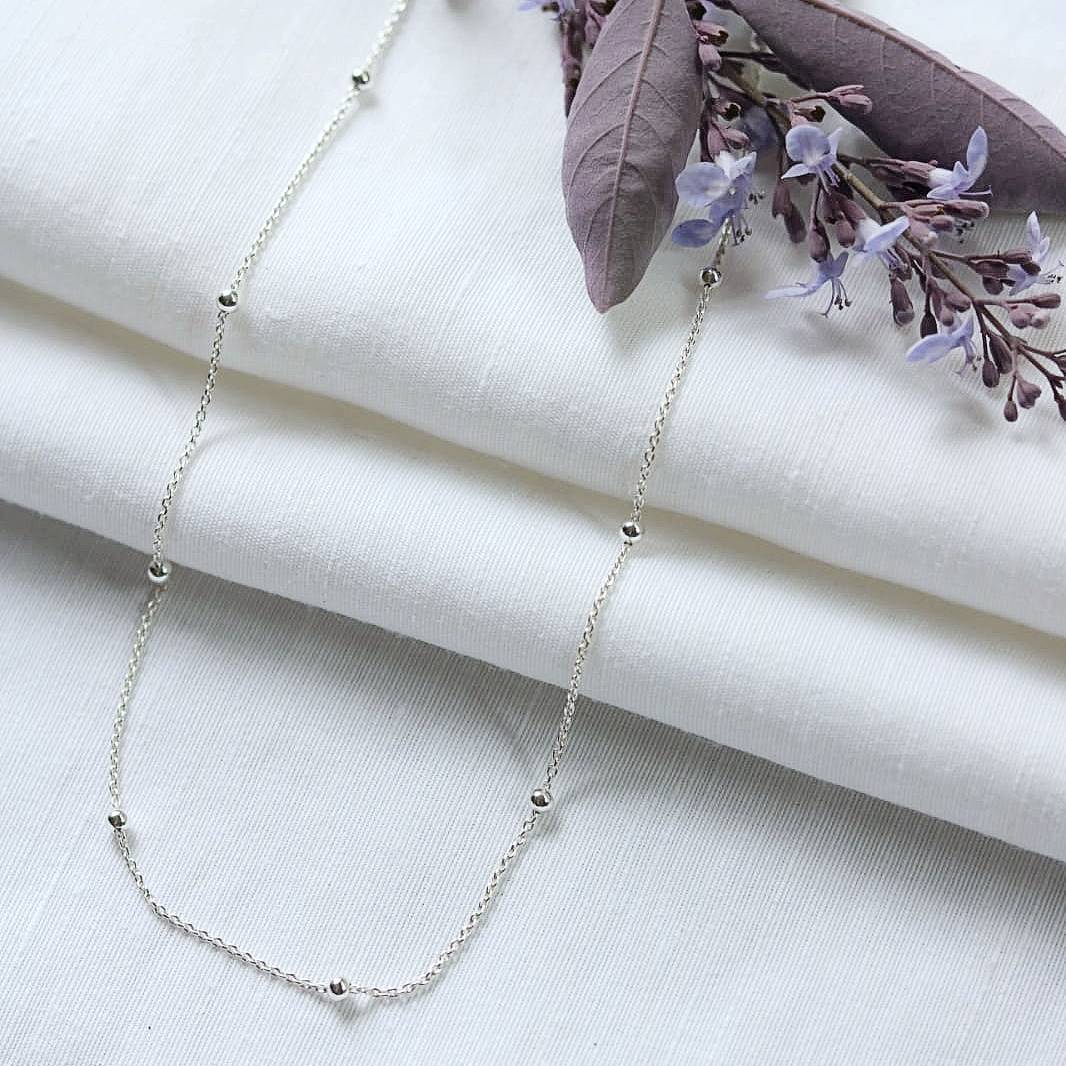 Sterling silver chain with sterling silver beads, shown on white linen