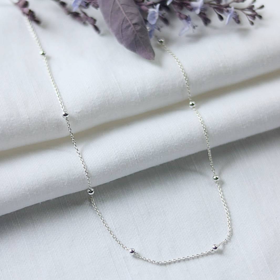 Sterling silver chain with sterling silver beads, shown on white linen