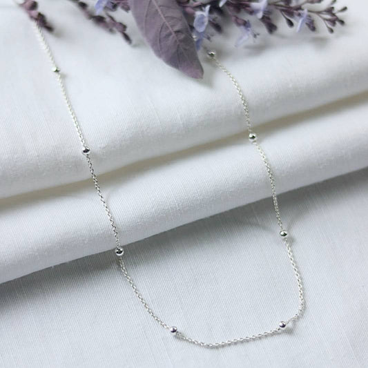 Sterling silver chain with sterling silver beads, shown on white linen
